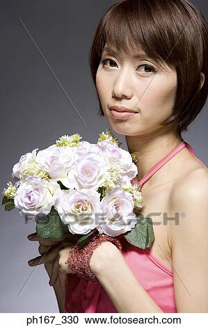 Stock Image - Woman in a red dress, holding a bouquet of flowers. Fotosearch
