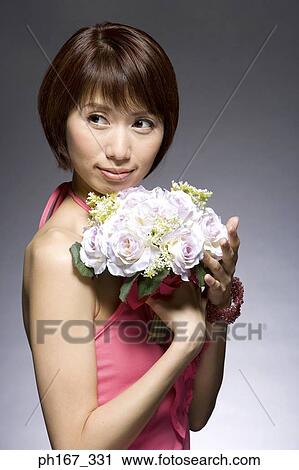 Stock Image - Woman in a red dress, holding a bouquet of flowers. Fotosearch