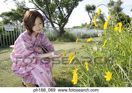Stock Photo - Woman in kimono enjoying the wild flowers. Fotosearch