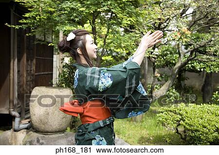 Stock Image - Woman in kimono having fun in the garden. Fotosearch