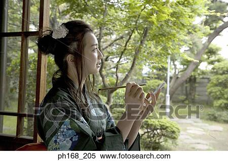 Stock Photography - Woman in kimono holding a paintbrush and book. Fotosearch