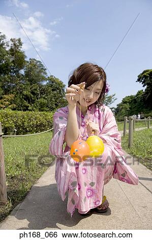 Stock Photograph - Woman in kimono playing with balloons. Fotosearch