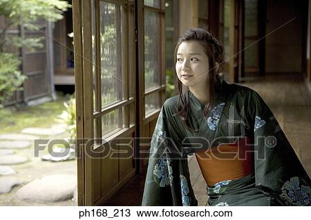 Stock Image - Woman in kimono sitting by the corridor, looking out. Fotosearch
