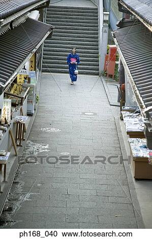Stock Image - Woman in kimono walking down an alley, high angle view. Fotosearch