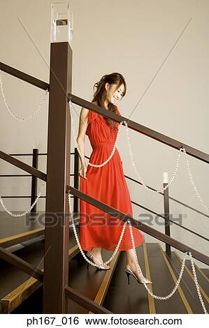Stock Photograph - Woman in red dress walking down stairs. Fotosearch