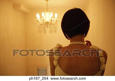 Picture - Woman looking at chandelier, rear view. Fotosearch