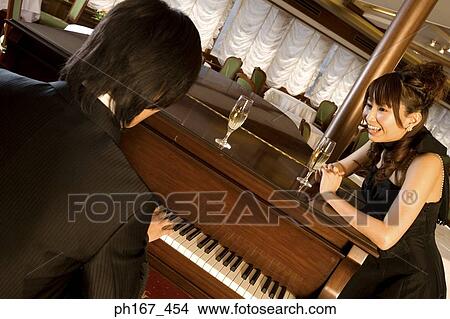 Picture - Woman looking at man playing piano. Fotosearch