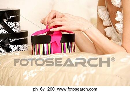Woman lying in bed, unwrapping gifts View Large Photo Image Stock Image - Woman lying in bed, unwrapping gifts. Fotosearch