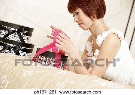 Woman lying in bed, unwrapping gifts, close-up View Large Photo Image Stock Image - Woman lying in bed, unwrapping gifts, close-up. Fotosearch