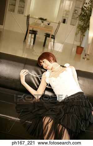 Stock Image - Woman lying on leather sofa. Fotosearch