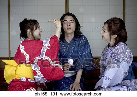 Stock Image - Woman painting a man's eyebrows. Fotosearch