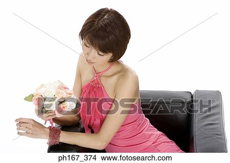 Woman sitting on a sofa with a bouquet of roses View Large Photo Image Picture - Woman sitting on a sofa with a bouquet of roses. Fotosearch