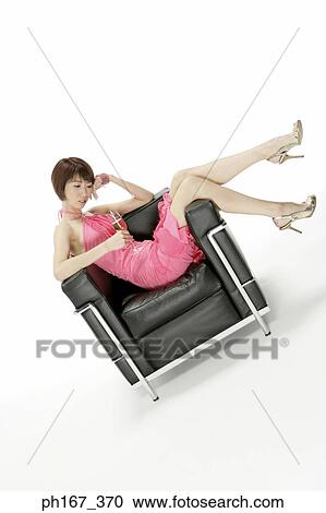 Stock Image - Woman sitting on a sofa with a glass of champagne. Fotosearch