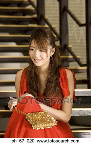 Stock Image - Woman sitting on stairs, smiling. Fotosearch