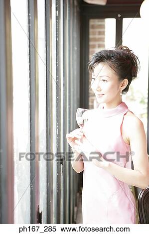 Woman standing by the window with a glass of white wine View Large Photo Image Stock Photography - Woman standing by the window with a glass of white wine. Fotosearch