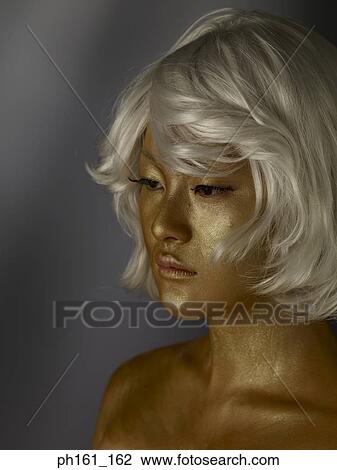 Woman wearing a blonde wig with gold paint on her face View Large Photo Image Stock Image - Woman wearing a blonde wig with gold paint on her face . Fotosearch