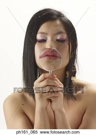 Stock Photography - Woman with a magnifying glass on her mouth. Fotosearch