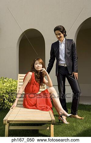 Young couple relaxing in the courtyard, woman sitting on deck chair View Large Photo Image Stock Image - Young couple relaxing in the courtyard, woman sitting on deck chair. Fotosearch
