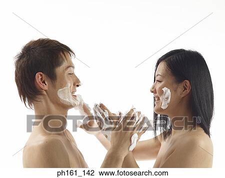 Stock Image - Young couple with cream on their faces and hands. Fotosearch