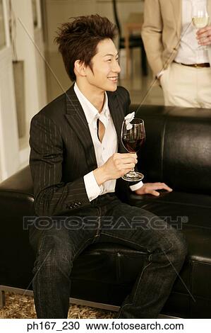 Young man relaxing with a glass of wine View Large Photo Image Stock Image - Young man relaxing with a glass of wine. Fotosearch