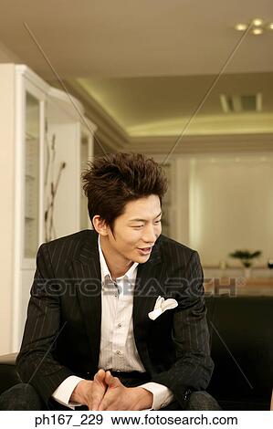 Young man sitting on a sofa View Large Photo Image Stock Photo - Young man sitting on a sofa. Fotosearch