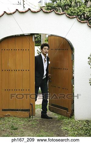 Young man walking through wooden door View Large Photo Image Stock Photo - Young man walking through wooden door. Fotosearch