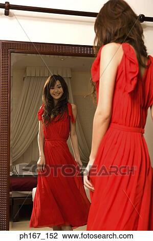 Young woman adjusting dress in front of mirror View Large Photo Image Stock Image - Young woman adjusting dress in front of mirror. Fotosearch