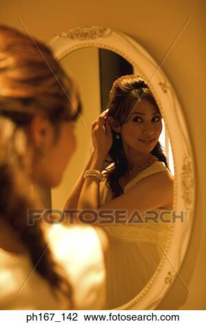 Young woman looking at reflection in mirror View Large Photo Image Stock Image - Young woman looking at reflection in mirror. Fotosearch
