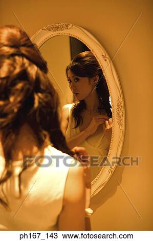 Young woman looking at reflection in mirror View Large Photo Image Stock Image - Young woman looking at reflection in mirror. Fotosearch