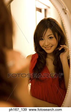 Young woman looking at reflection in mirror View Large Photo Image Stock Photo - Young woman looking at reflection in mirror. Fotosearch