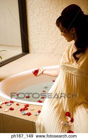 Young woman sitting by bath tub with rose petals View Large Photo Image Stock Photo - Young woman sitting by bath tub with rose petals. Fotosearch