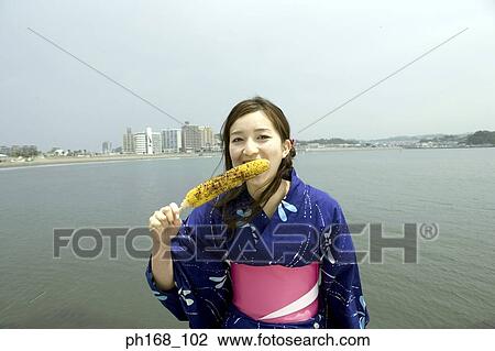 Young woman taking a bit off roasted corn View Large Photo Image Stock Image - Young woman taking a bit off roasted corn. Fotosearch