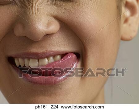 Picture - Young woman's mouth with tongue licking lips, close-up. Fotosearch