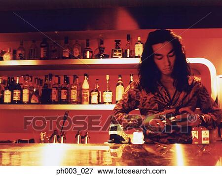 Stock Photo - Bartender mixing drinks at a bar counter . Fotosearch