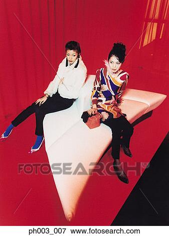 Two Asian women sitting on odd shape sofa View Large Photo Image Stock Photo - Two Asian women sitting on odd shape sofa. Fotosearch