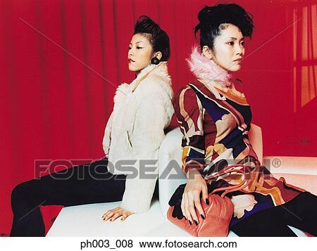 Two Asian women sitting on white sofa View Large Photo Image Stock Photo - Two Asian women sitting on white sofa. Fotosearch