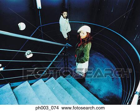Picture - Two women standing at stairs landing. Fotosearch