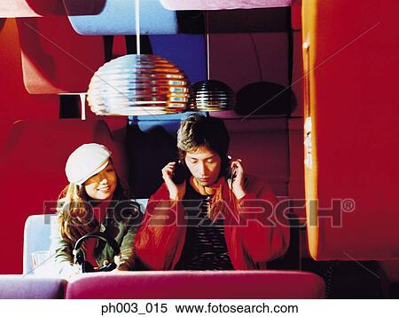 Stock Photography - Young couple listening to headphones in a restaurant. Fotosearch