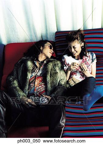 Young couple on a sofa, smiling View Large Photo Image Stock Image - Young couple on a sofa, smiling . Fotosearch