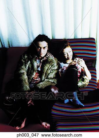 Stock Photo - Young couple on a sofa, smiling . Fotosearch