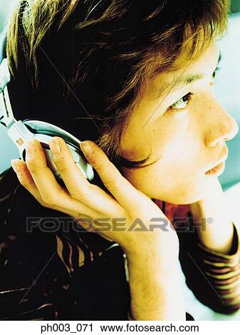 Stock Image - Young man listening to headphones, profile, close up. Fotosearch