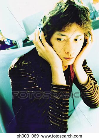 Stock Photo - Young man listening to headphones, portrait, close up. Fotosearch