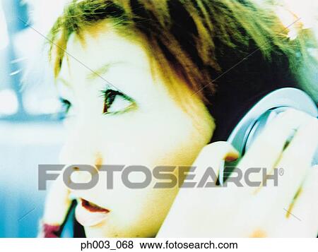 Stock Photo - Young woman listening to headphones, profile, close up. Fotosearch