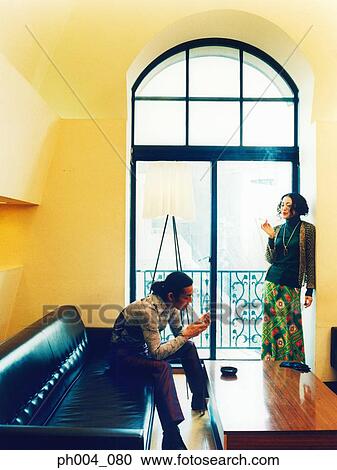 Man sitting on a sofa, woman standing against wall, smoking cigarettes View Large Photo Image Stock Image - Man sitting on a sofa, woman standing against wall, smoking cigarettes. Fotosearch