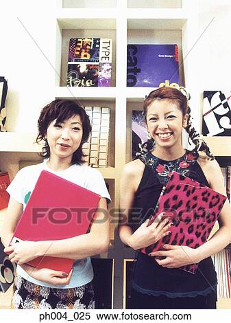 Two young woman smiling, carrying books View Large Photo Image Stock Photography - Two young woman smiling, carrying books. Fotosearch