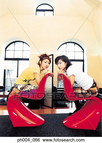 Stock Photograph - Two young women sitting across from each other. Fotosearch