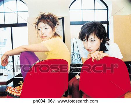 Two young women sitting beside each other View Large Photo Image Stock Photo - Two young women sitting beside each other. Fotosearch
