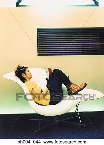 Woman reading book on curved chair View Large Photo Image Picture - Woman reading book on curved chair. Fotosearch