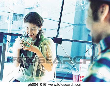 Stock Photograph - Young couple chatting, laughing and drinking. Fotosearch