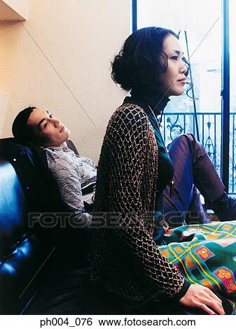 Stock Photograph - Young couple sitting on a sofa, portrait. Fotosearch